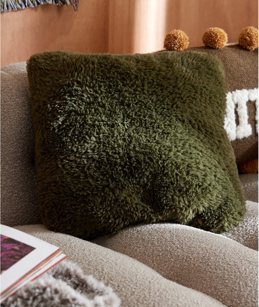 Coussin Dalvin tricoté en fausse fourrure kaki foncé, 40 x 40 cm, posé sur un canapé bouclette - Patron tricot Pingouin