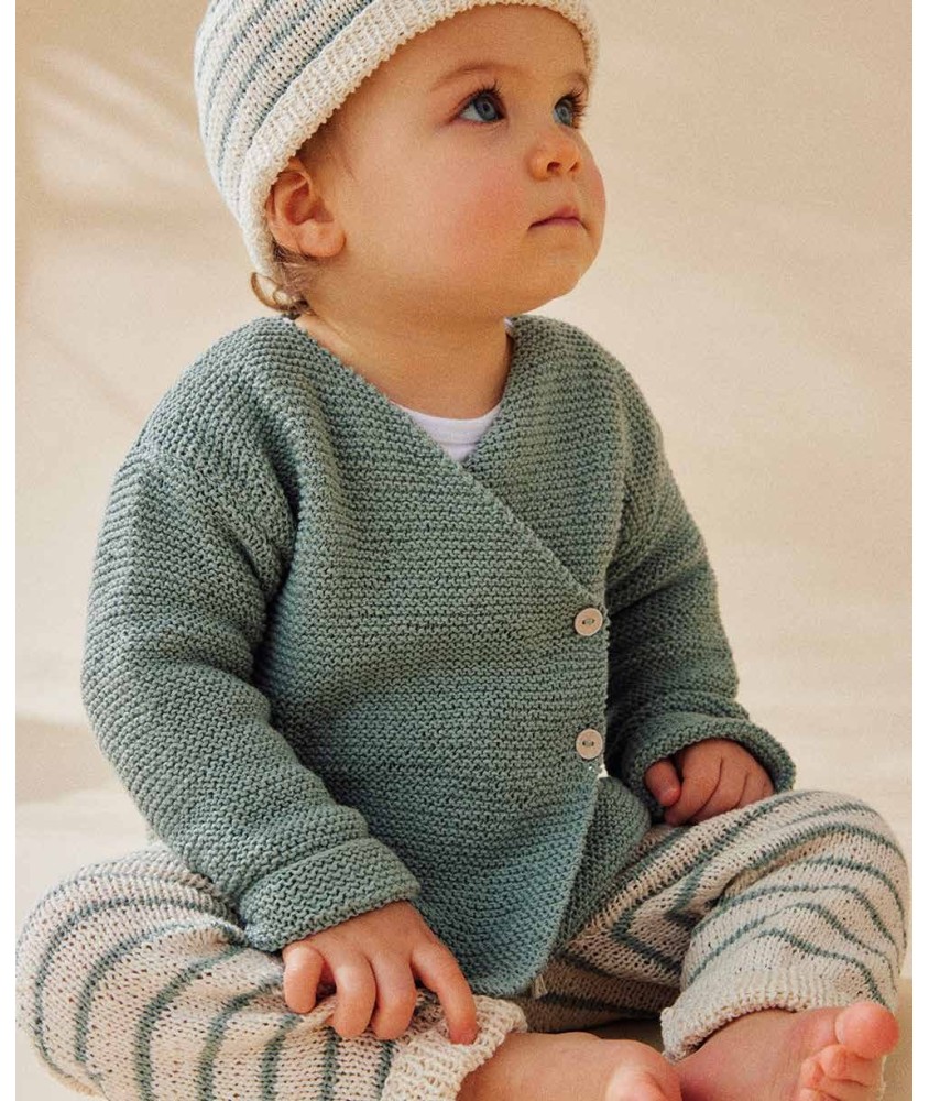 Brassière cache-coeur Tess en coton amande, portée par un bébé avec un bonnet - Patron tricot Phildar