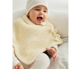 Poncho Bowie tricoté au point mousse écru avec une cordelière à pompons, sur un bébé - Patron tricot Phildar