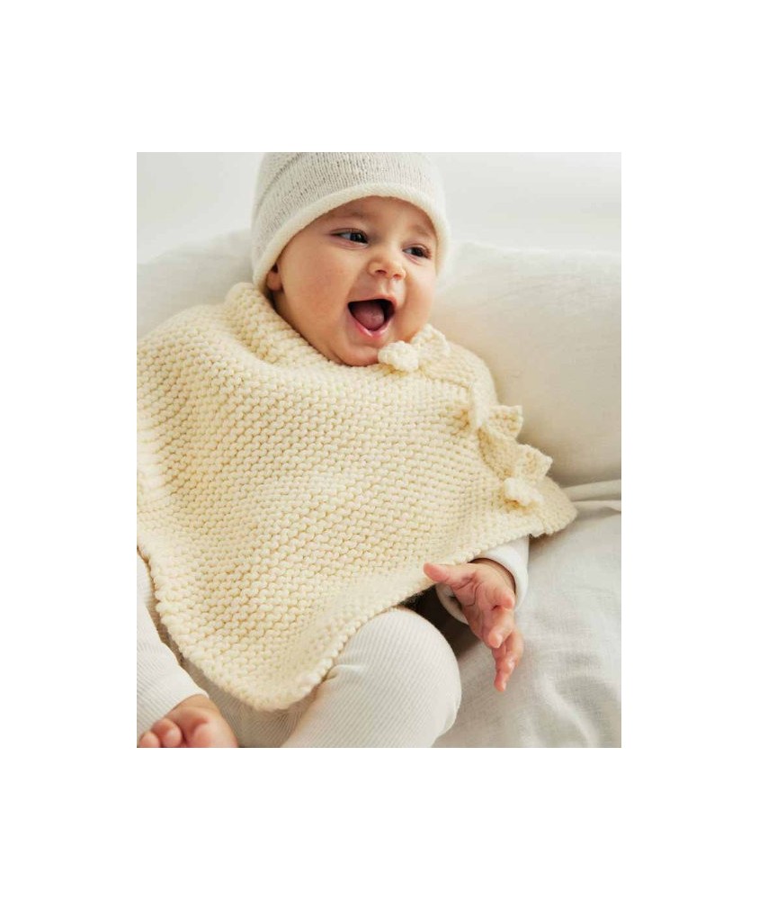 Poncho Bowie tricoté au point mousse écru avec une cordelière à pompons, sur un bébé - Patron tricot Phildar