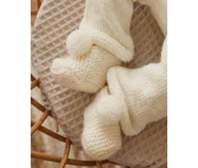 Chaussons Lambert tricotés au point mousse écru, posés sur un coussin - Patron tricot Phildar