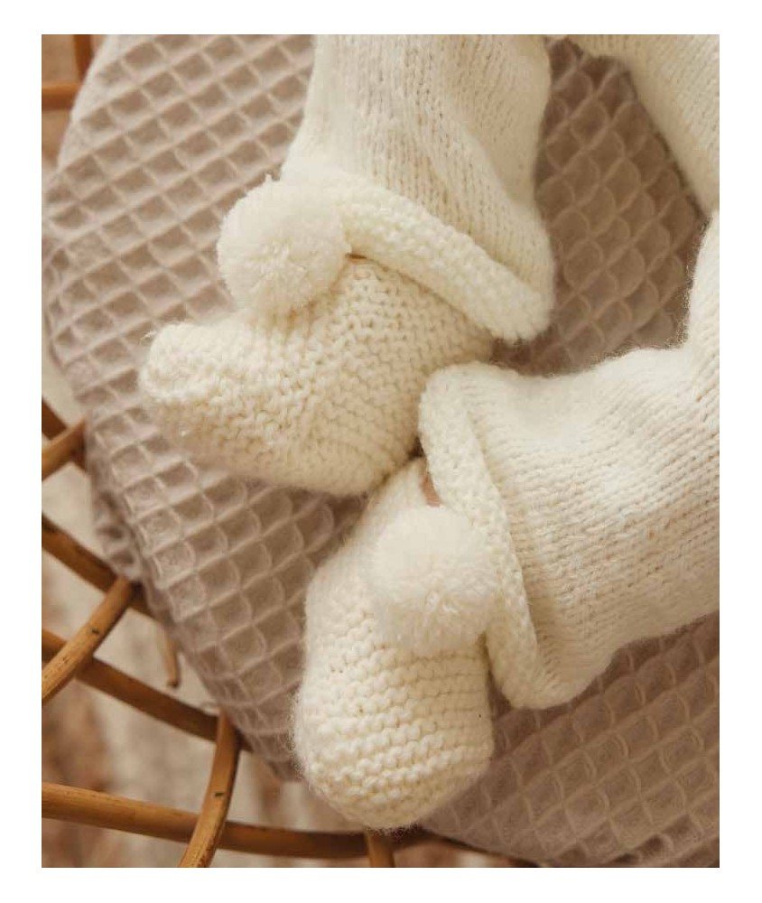 Chaussons Lambert tricotés au point mousse écru, posés sur un coussin - Patron tricot Phildar