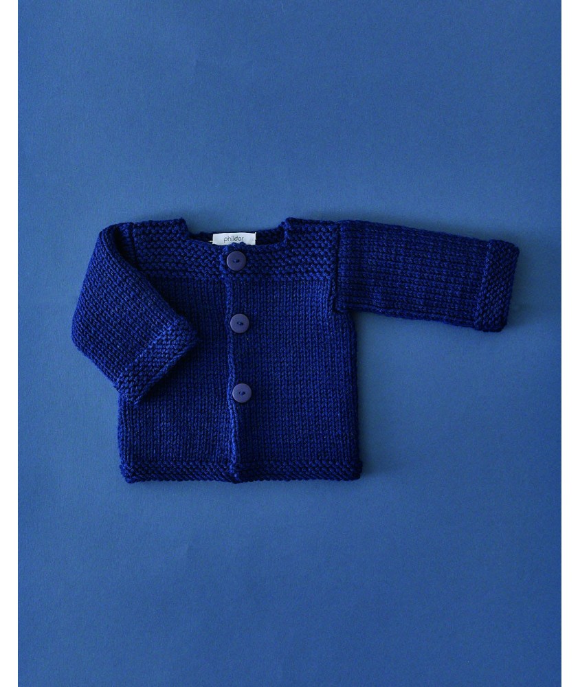 Paletot Léandre tricoté en bleu marine, trois boutons, posé à plat sur fond bleu - Patron tricot Phildar