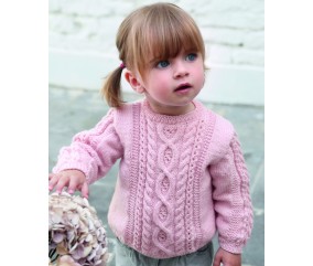Pull Isalys rose à torsades et motifs de cœurs en relief, porté par une petite fille - Patron tricot Phildar